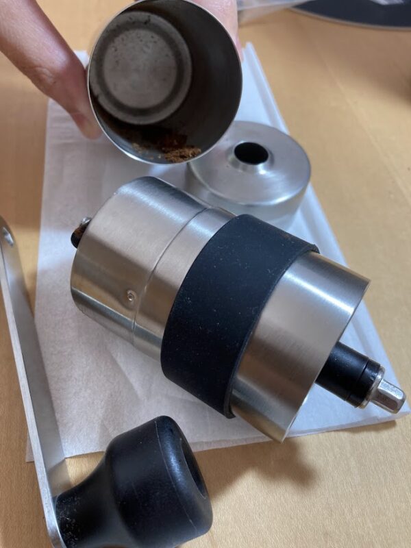 キャプテンスタッグのコーヒーミルで豆を数回挽き、受け容器を外して粉の粗さを確認している様子
