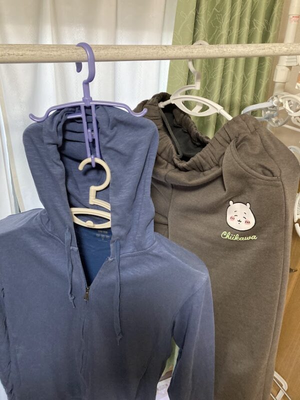 ダイソーのフードハンガーを使い、パーカーのフードを浮かせて部屋干し効率を上げている写真。隣にはちいかわのスウェットが干してある。