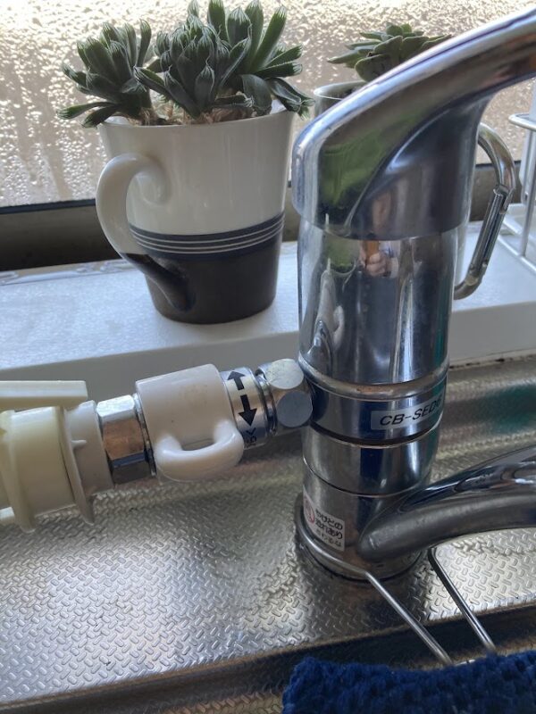 キッチンの蛇口に分岐水栓を取り付け、給水ホースを接続して水漏れがないか確認している様子