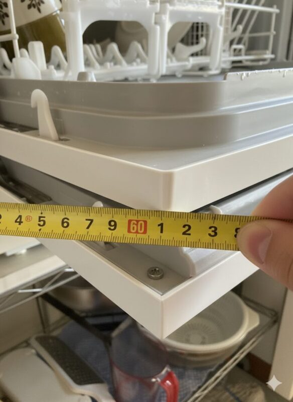 食洗機のドアを全開にしてメジャーで奥行きを測り、約60cmあることを確認している様子