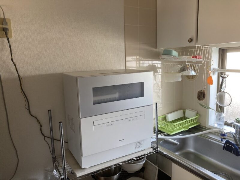 キッチンのシンク横にスチールラックを使って設置されたパナソニックの卓上食洗機の様子