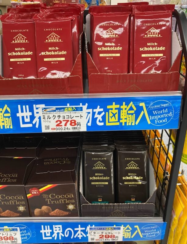 業務スーパーで人気のドイツ産100g板チョコ（ミルク・ビター）の売り場。ミルク278円、ビター298円の価格表示と、分厚いパッケージが特徴。