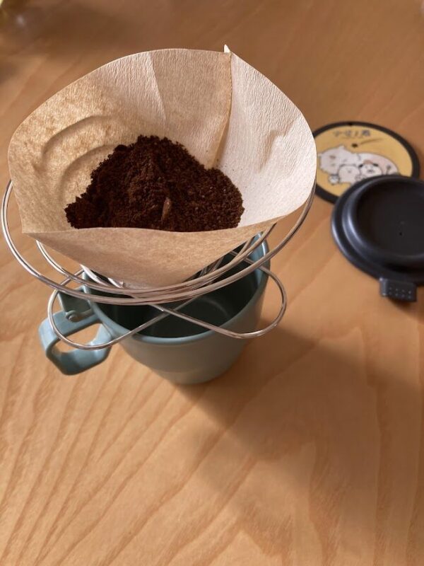 コーヒー豆をフィルターに入れて、抽出できるようにコップに置いている画像。