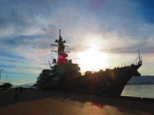 逆光に照らされる自衛隊の護衛艦のシルエットと海の風景