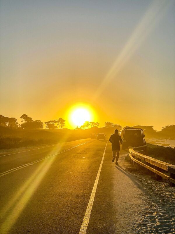 黄金色の夕日に向かって、海岸沿いの道を一人で走り込み特訓をする男性の背中