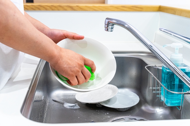 スポンジで泡立ててお皿を手洗いしている面倒な水仕事の様子