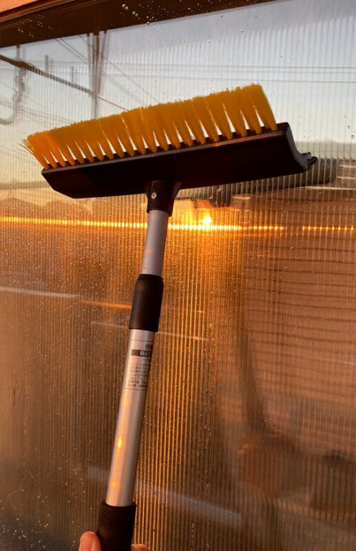 車の雪かき用スノーブラシを代用して家の窓掃除をしている様子