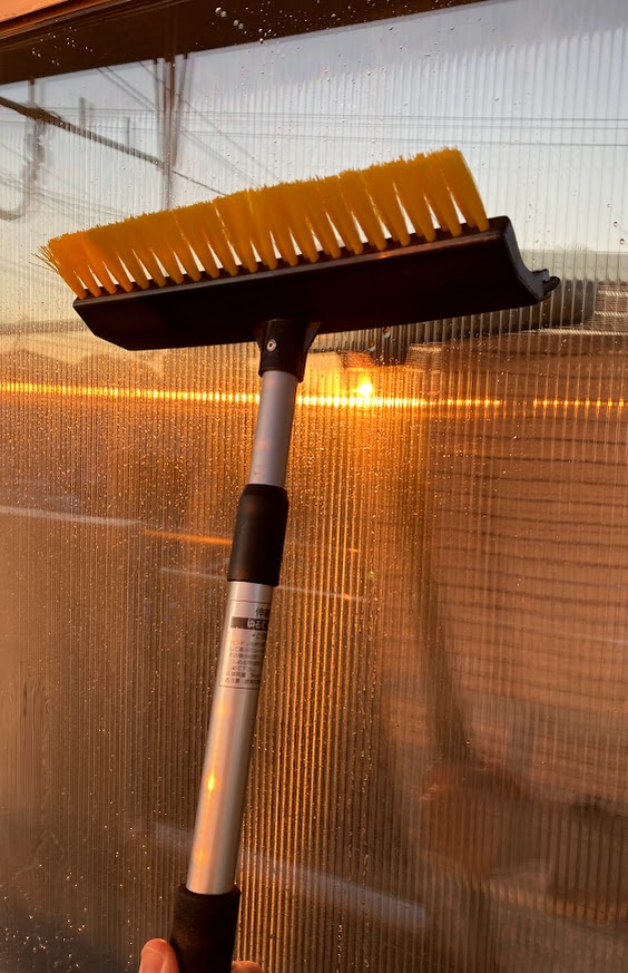 車の雪かき用スノーブラシを代用して家の窓掃除をしている様子