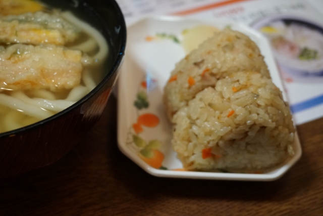 福岡のうどん店「小麦冶」のごぼう天うどんとかしわおにぎり。黄金色のスープと、味が染みてそうなかしわおにぎりのアップ。