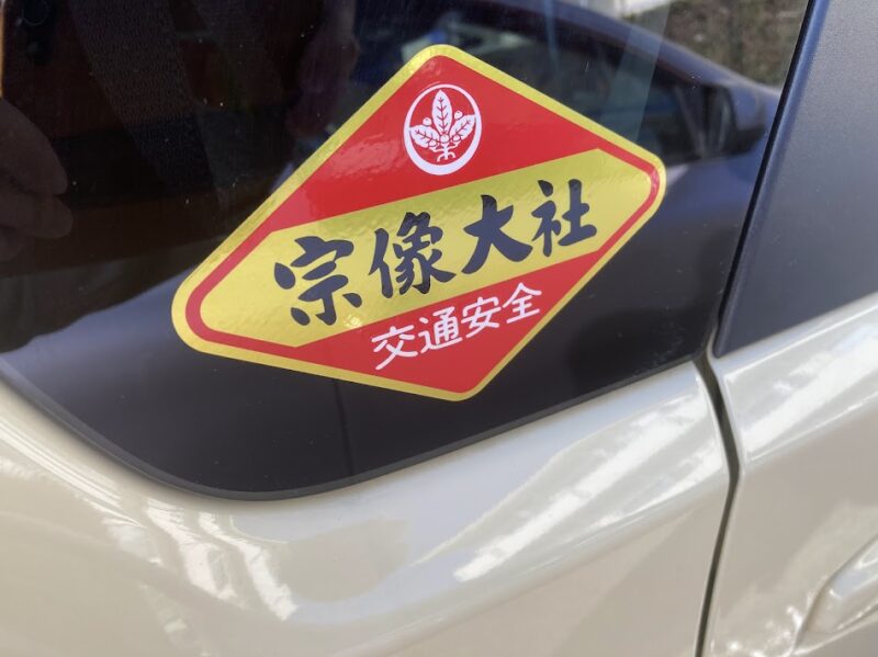 新型ワゴンRのリアガラスに貼られた宗像大社の交通安全ステッカー。赤と黄色の菱形で「宗像大社 交通安全」と書かれている。