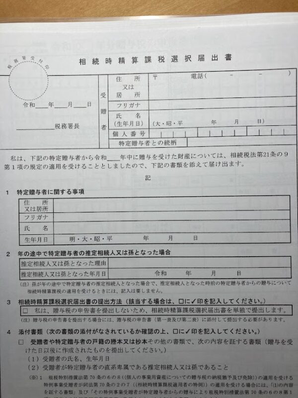 相続時精算課税選択届出書が未記入の書類。木の机の上に置かれている画像。