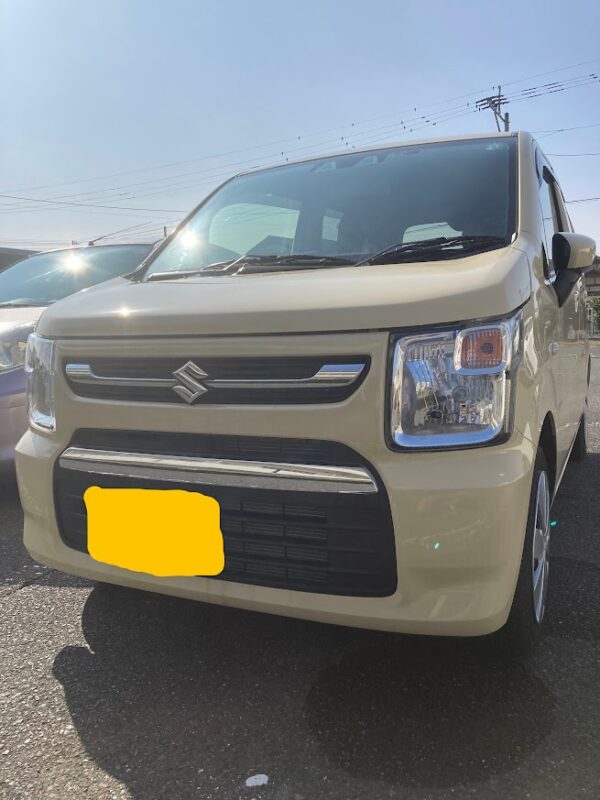 晴天の下、駐車場に停車しているベージュのスズキ・ワゴンRの外観写真