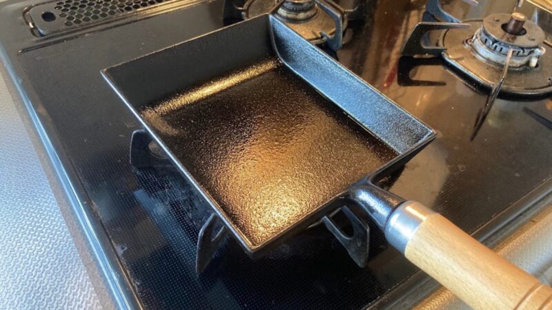 コンロの五徳の上に置かれた、油が綺麗に馴染んで黒光りする岩鋳の南部鉄器製卵焼き器