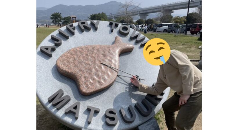 道の駅 松浦にある「アジフライの聖地」モニュメントと箸を持つ男性のユニークな記念写真