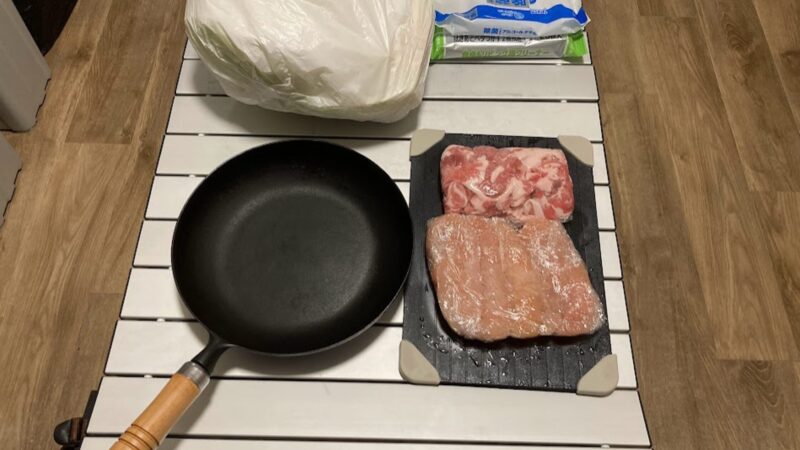 WAQワゴンのアルミテーブル上で、フライパンや食材を置いて調理の準備をしている風景。耐熱性のあるアルミ天板の活用例。