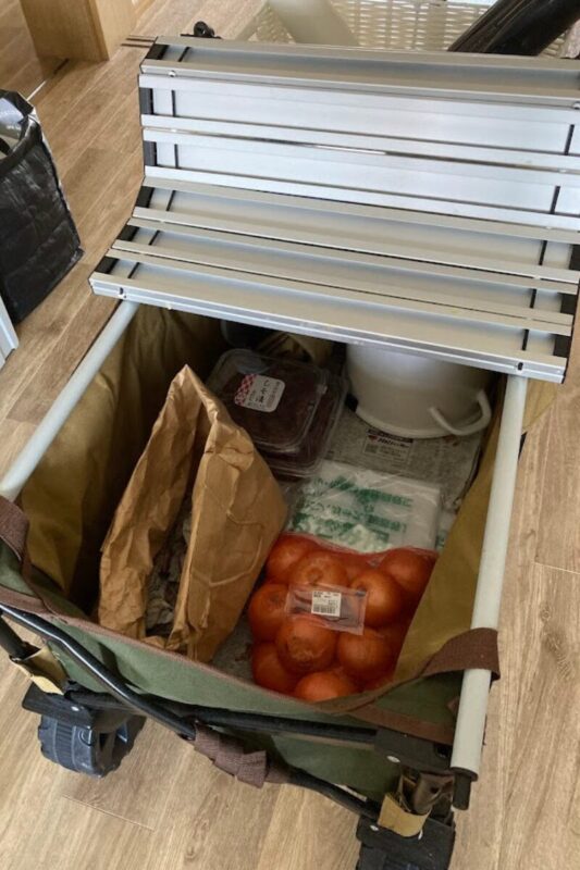 WAQワゴンのテーブルをめくり、中身に玉ねぎやじゃがいもなどの野菜をどっさり収納している様子