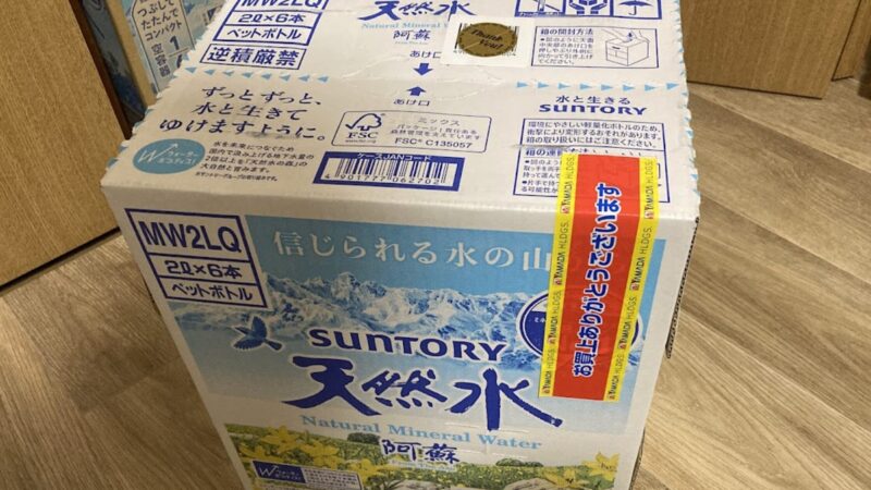 ヤマダ電機の500円割引券で購入したサントリー天然水(2L×6本入り)のケース。箱にはヤマダ電機の「お買上げありがとうございます」テープが貼られており、会員優待の500円券を生活必需品の備蓄に活用している様子。
