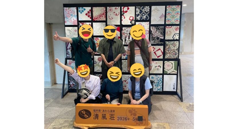 福井県あわら温泉の宿「清風荘」のロビーにて、華やかな和柄パネルと日付入り看板を前に笑顔のスタンプで顔を隠してポーズをとる親族一同の記念集合写真