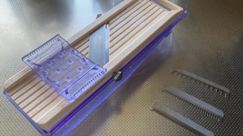 キッチン台に置かれた受け皿・安全カバー付きベンリナー本体と、横に並べられた3種類の交換用刃(平刃・細刃・荒刃)