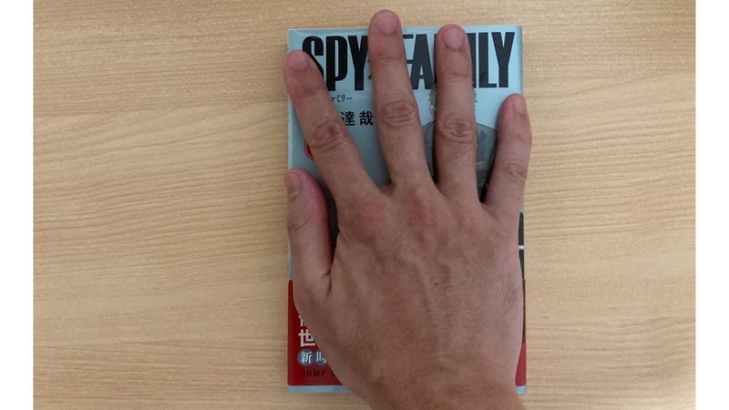 MX Master 3Sのサイズ感比較用に漫画の単行本に重ねた手の写真(手首から中指まで約19cm)
