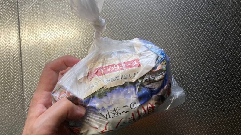 生ゴミを古紙(チラシ)で包み、空気を抜いてポリ袋の口を固く結んだ状態の写真