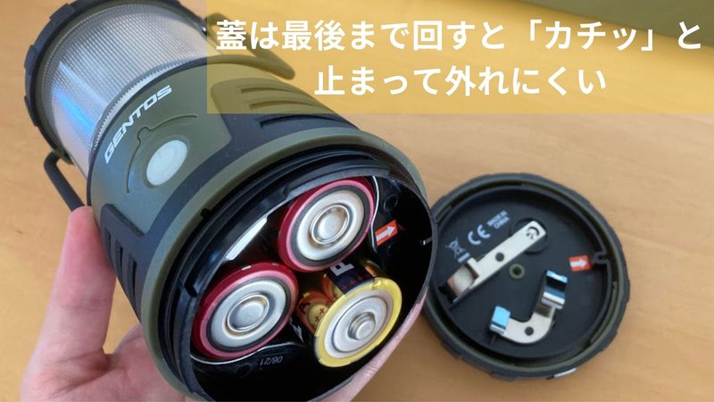 GENTOS(ジェントス)電池式ランタンの底蓋を開けた状態の写真。単1乾電池が3本入っており、画像上部には「蓋は最後まで回すと『カチッ』と止まって外れにくい」という文字テロップが入っている様子。