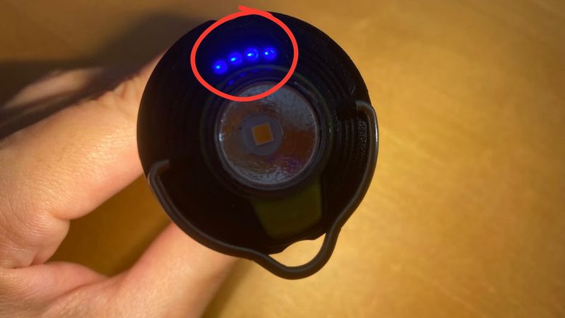 Goal Zero(ゴールゼロ)LIGHTHOUSE micro FLASH の3分割プレゼンテーション画像。左上は手のひらに載せて先端のフラッシュライトを点灯させている様子、左下は頂点から見た特写で4つの青色LED電池残量指示灯が点灯している様子(赤い丸はなし)、右側はテーブルの上に置いてランタンモードで周囲を照らしている様子。